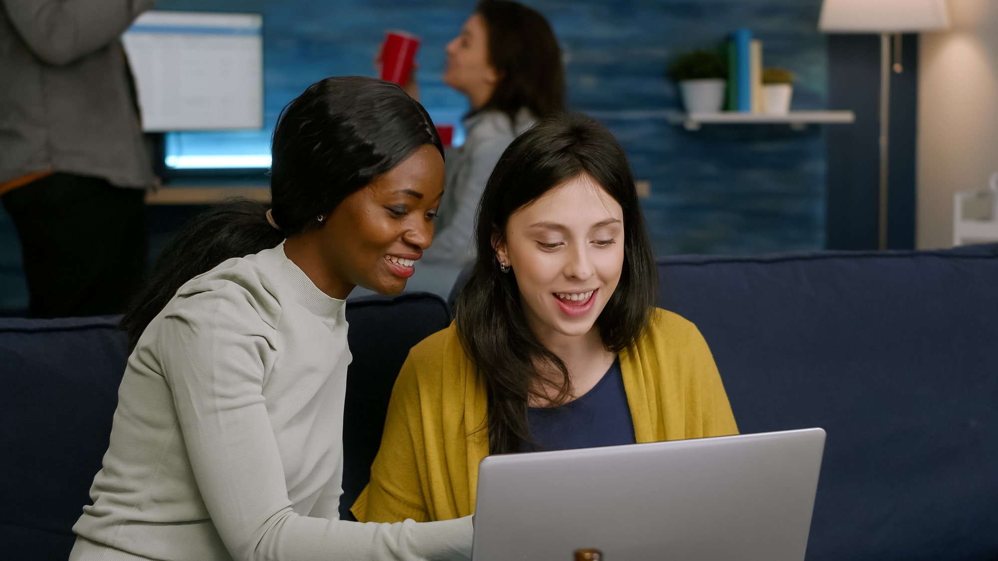 Multiracial friends laughing while watching funny video on laptop
